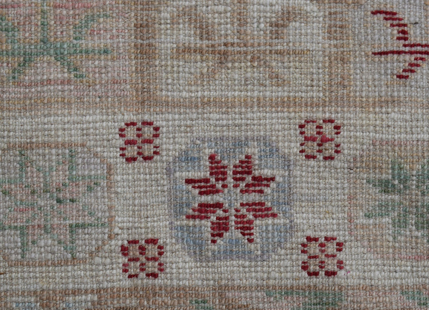 A handwoven Oushak runner featuring a geometric floral pattern in red, blue, and green on wool.
