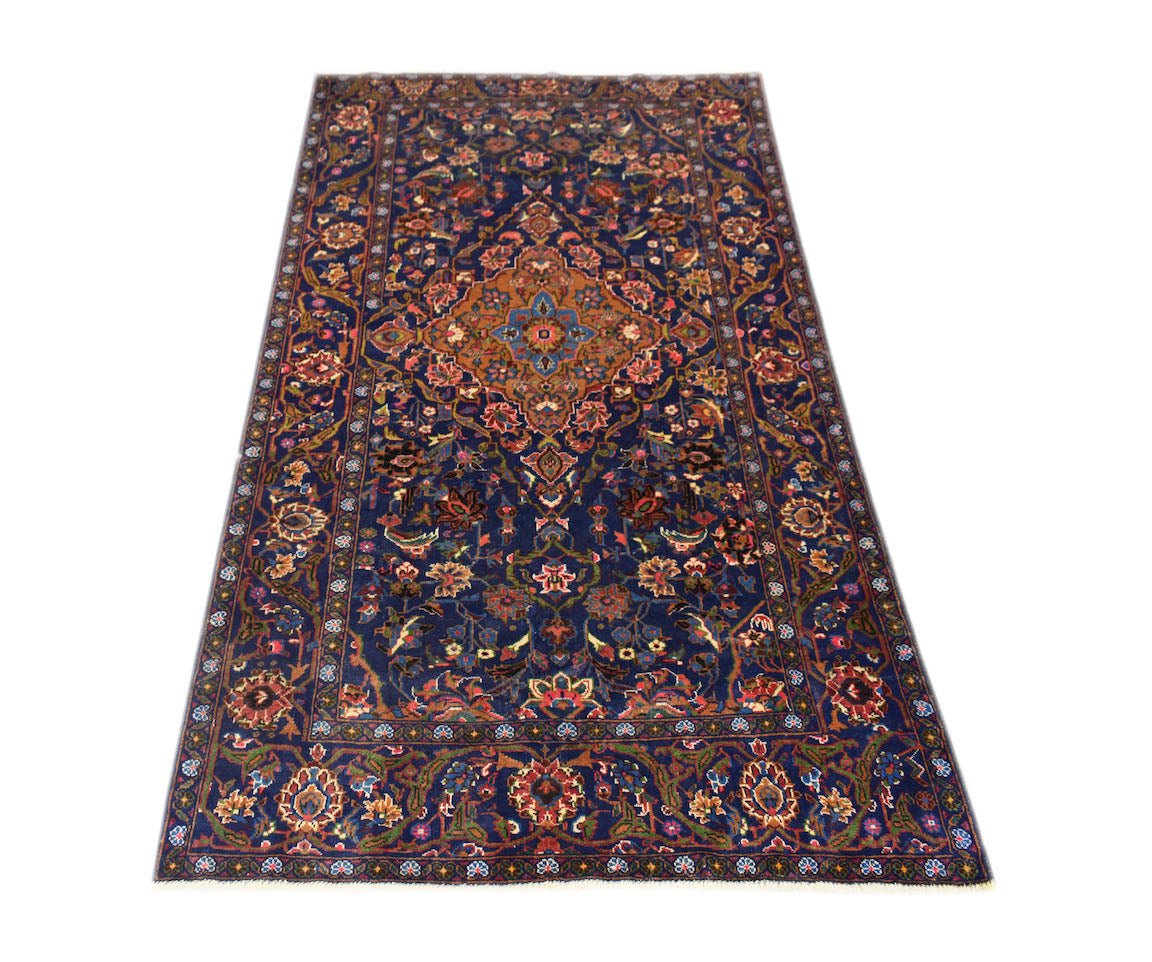 A rectangular vintage Afghan Baluch rug featuring a central medallion on a dark blue floral field.