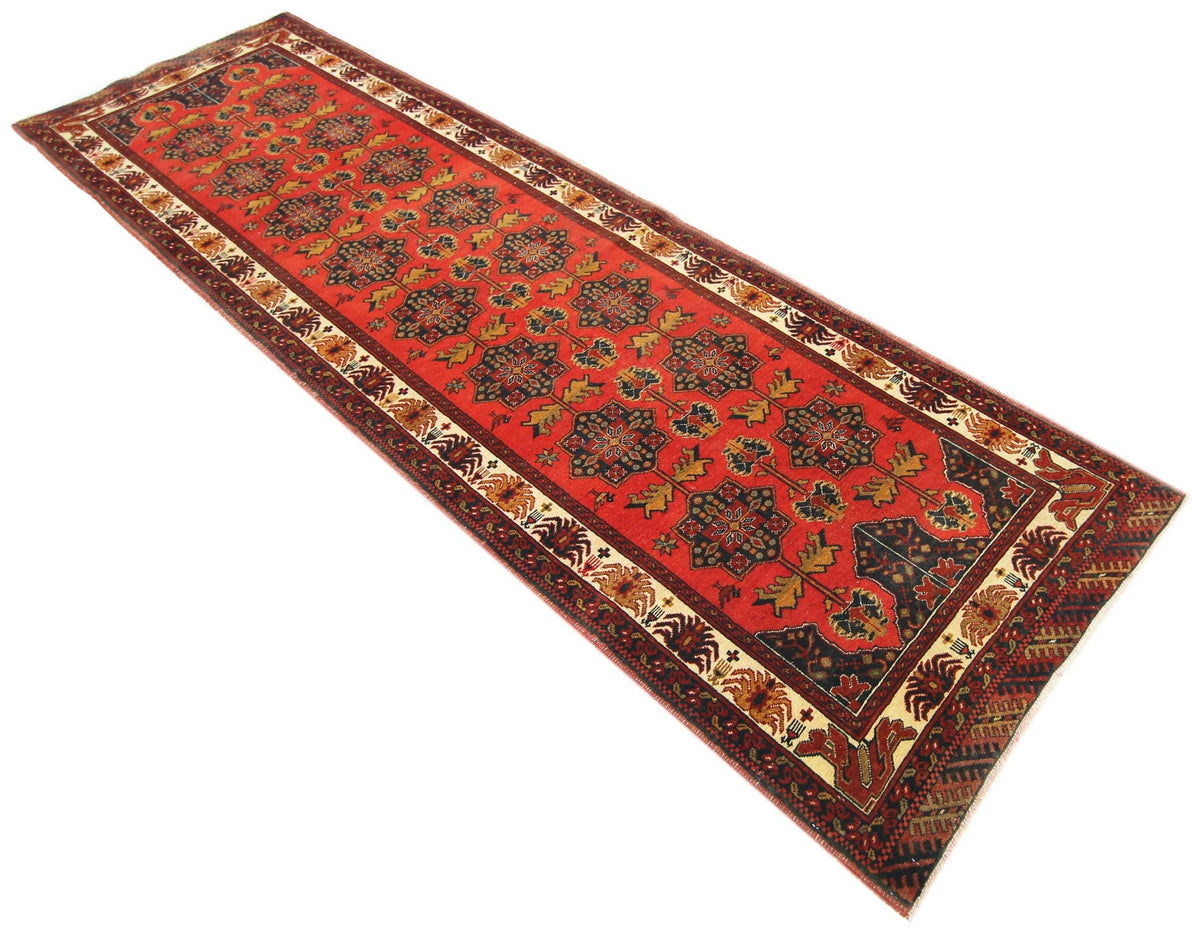 Vintage Afghan runner with a red field, repeating dark floral medallions, and a decorative cream and brown border.