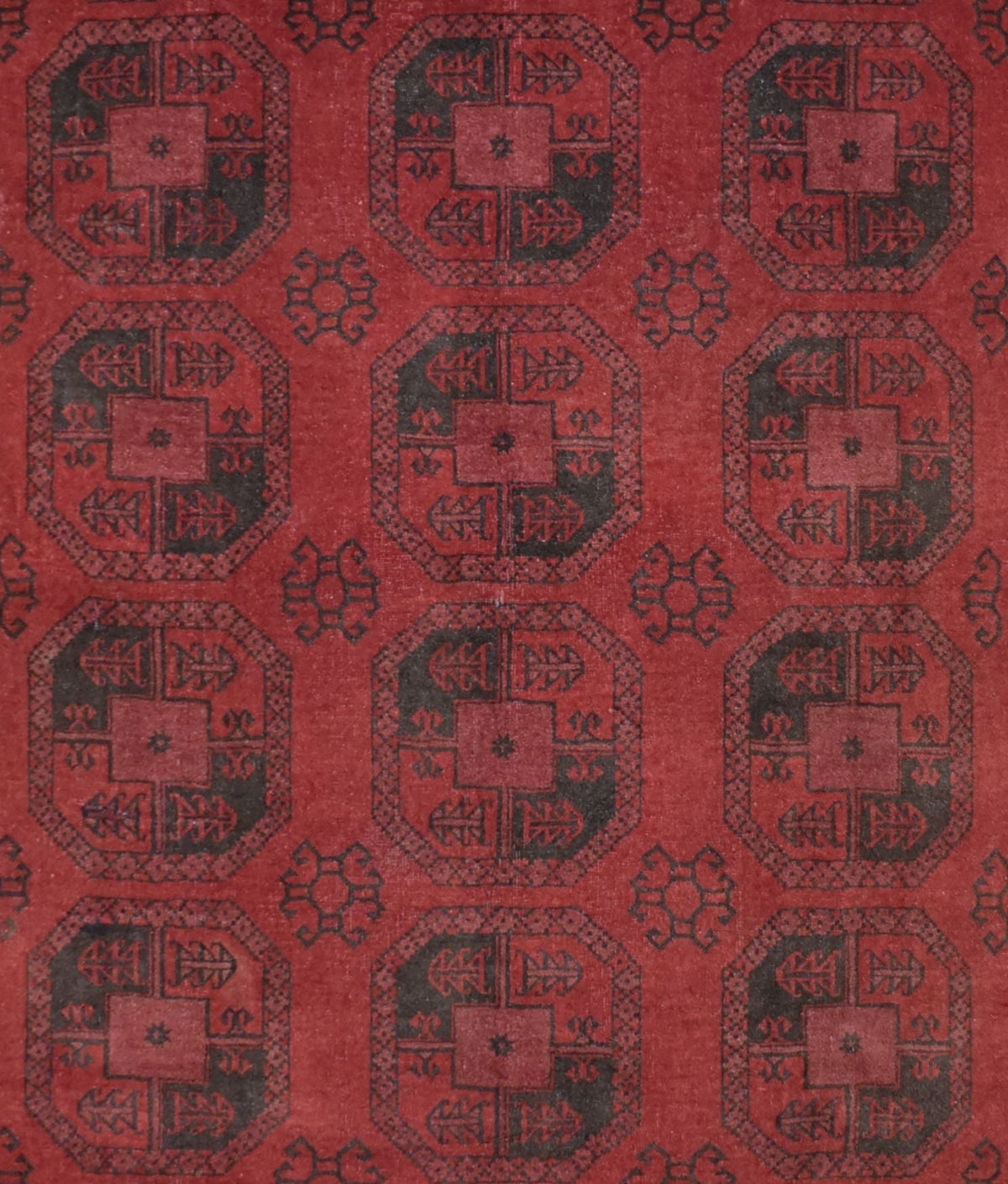 A vintage handmade Afghan Turkmen rug featuring a repeating geometric octagonal pattern in red and black.