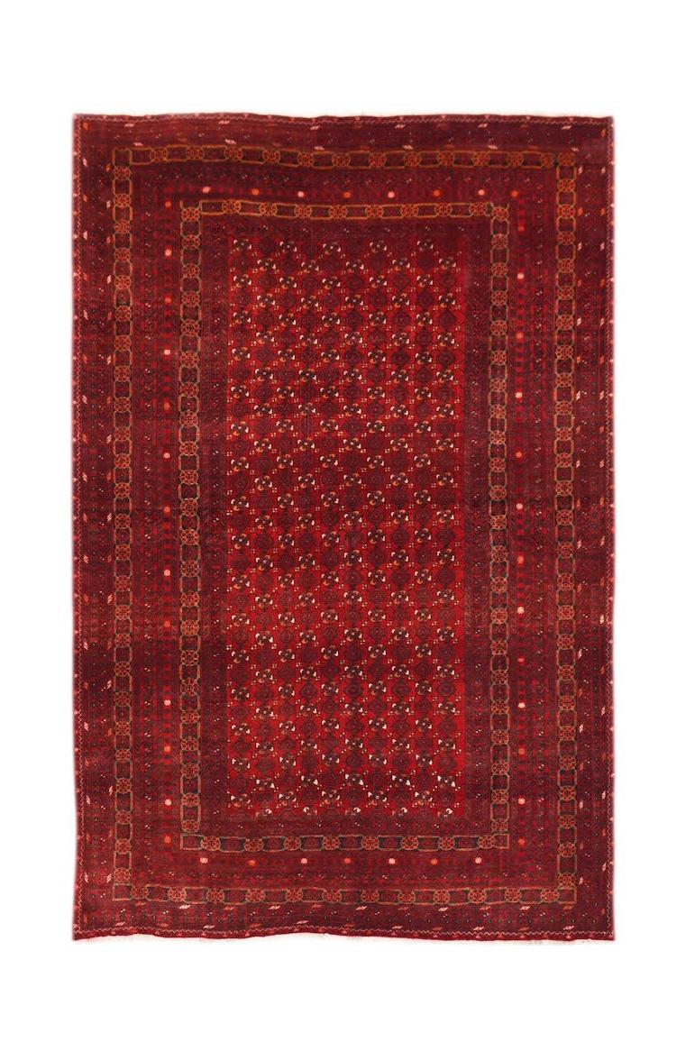 A vintage handmade Afghan Turkmen rug featuring a deep red field with repeating elephant foot motifs.