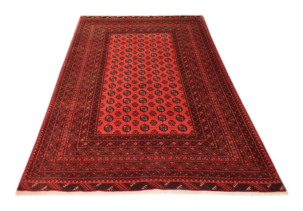 A vintage handmade Afghan Turkmen rug featuring a red field with repeating elephant foot motifs.