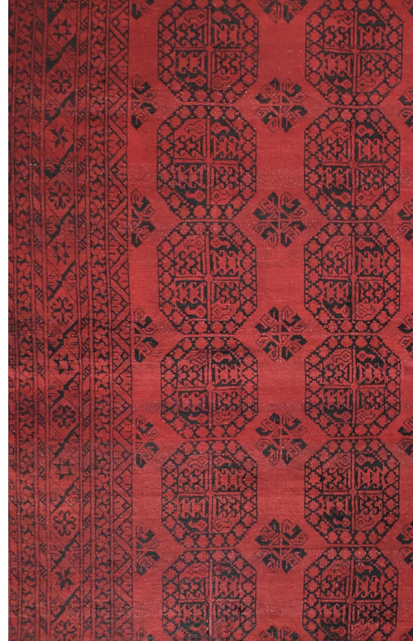 A vintage Afghan Turkmen rug featuring a repeating geometric octagonal pattern in red and black.