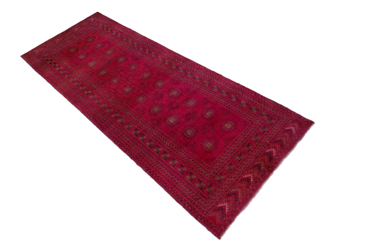 Hand-knotted Afghan Turkmen runner in deep red wool with repeating dark gul medallions and intricate geometric borders.