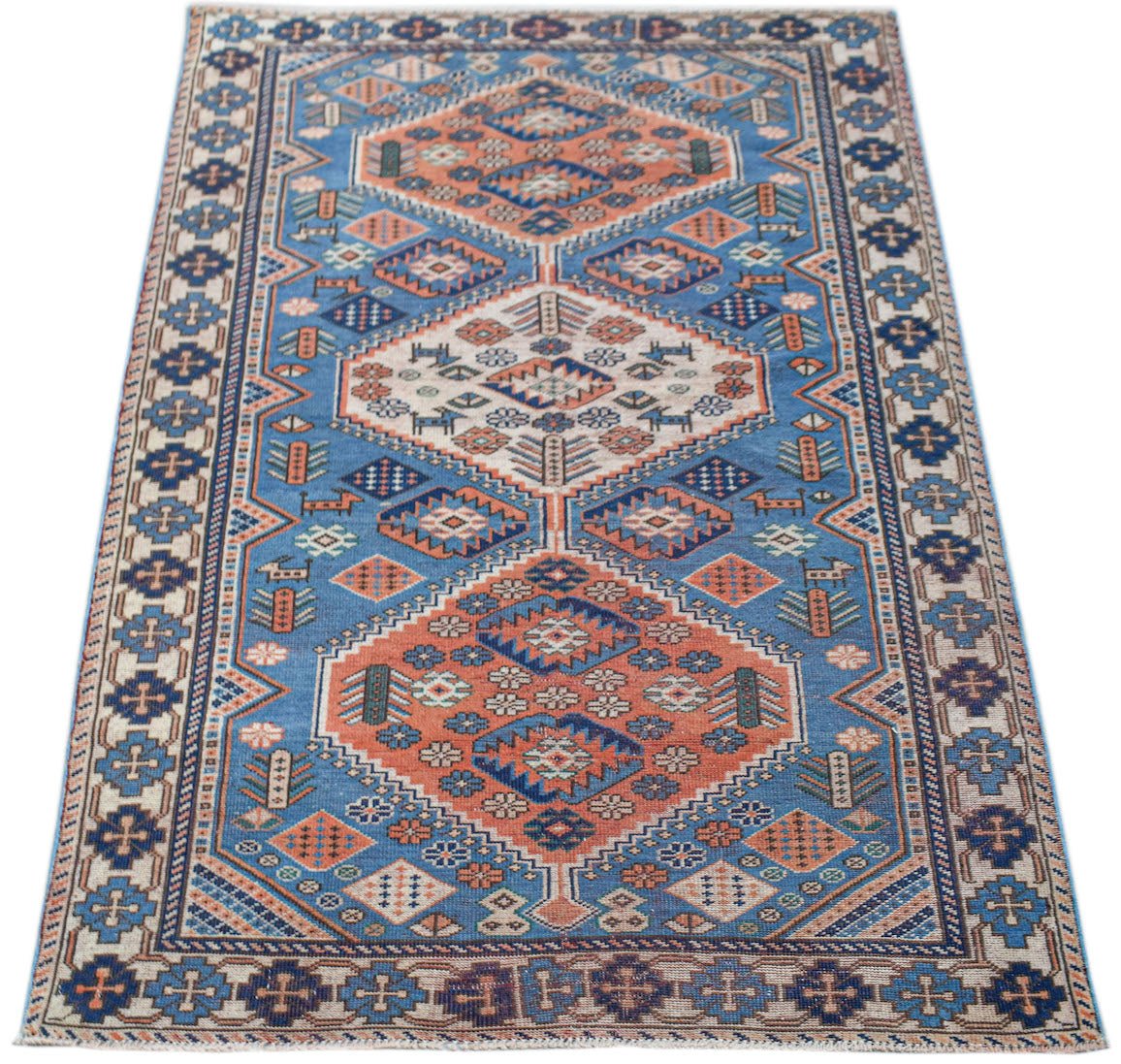 Handwoven vintage Caucasian rug featuring geometric diamond patterns in blue and orange tones.