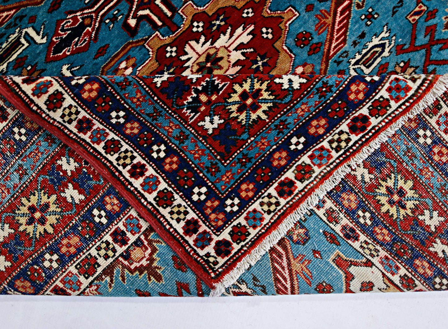 A vintage Caucasian Shirvan rug with intricate geometric patterns in blue, red, and cream.