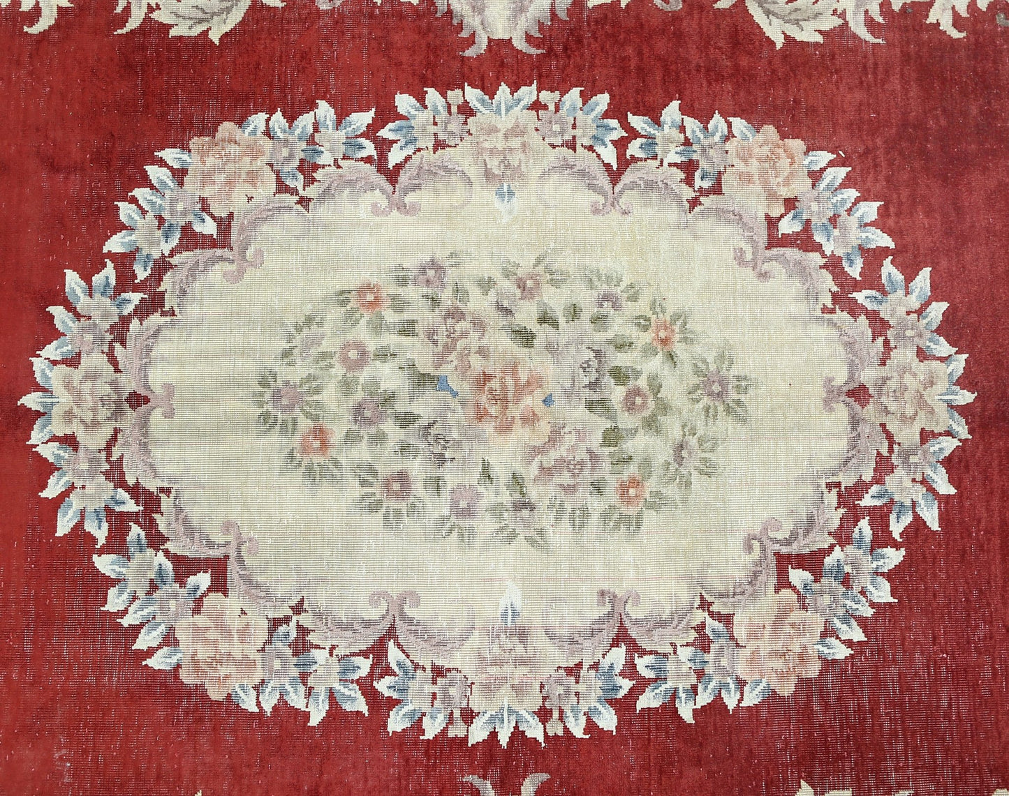 A vintage Chinese silk rug featuring a central floral medallion on a deep red background.