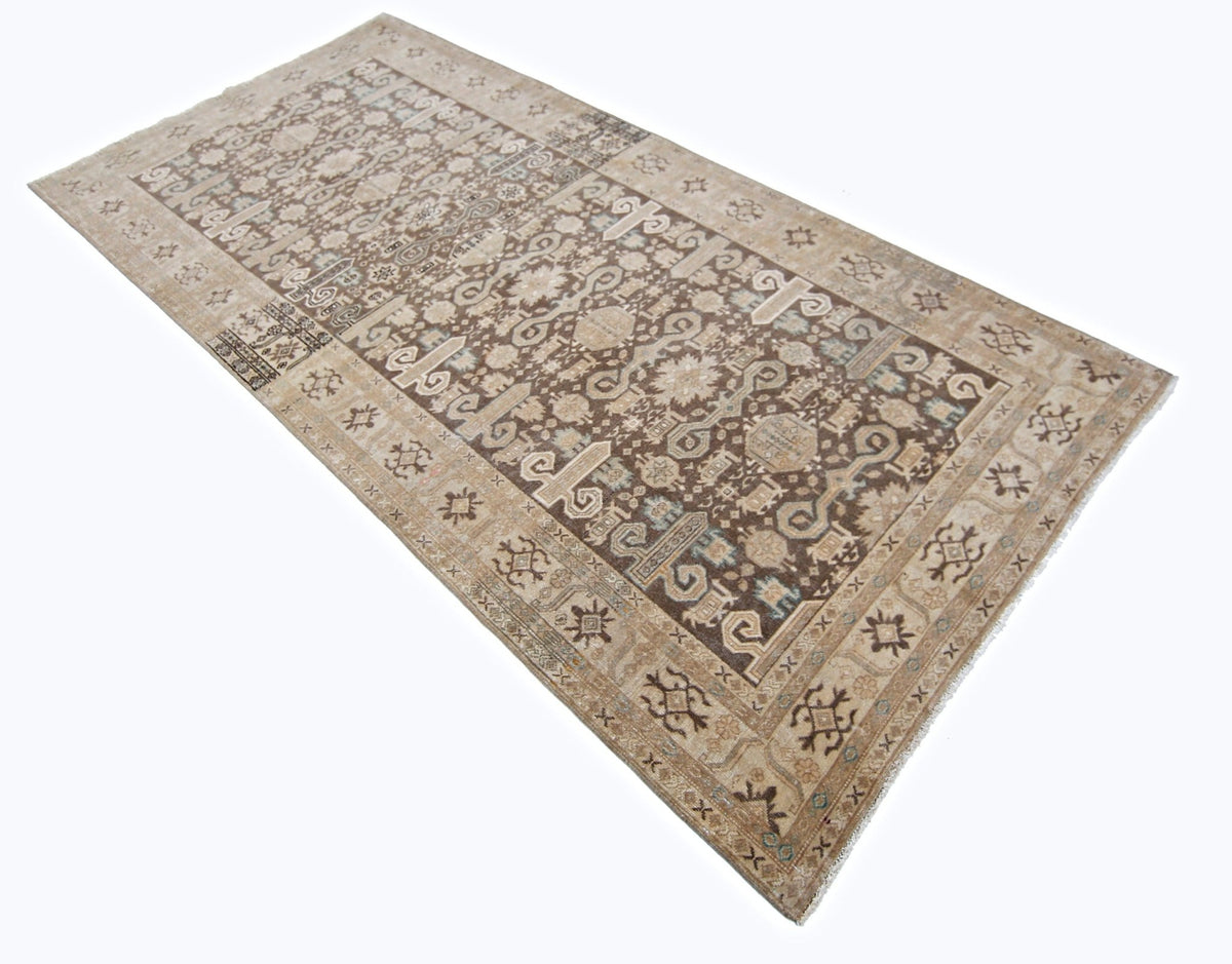 Hand-knotted vintage Khotan wool rug featuring a brown and beige geometric medallion pattern with a decorative border.