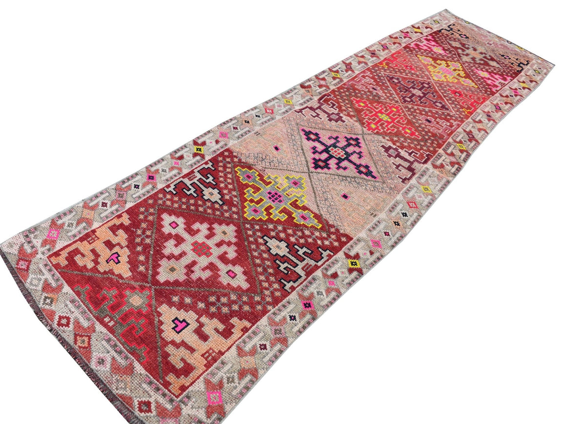 Vintage Kurdish Herki runner with tribal motifs in red, pink, and yellow.