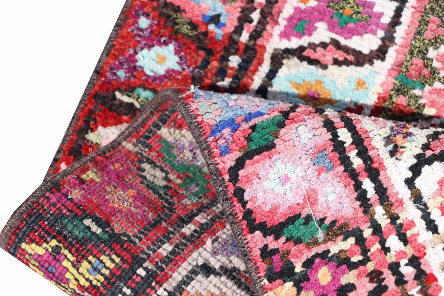 A vintage Kurdish Herki runner featuring vibrant tribal patterns and a folded corner.