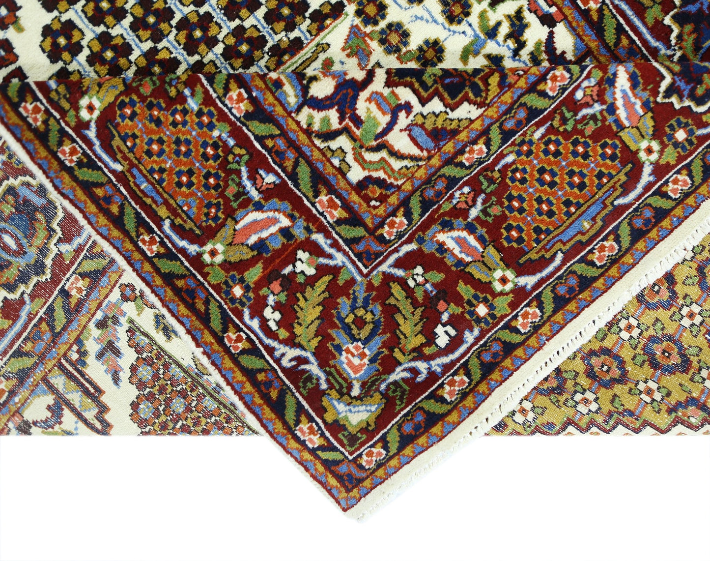 A folded vintage Pakistani wool rug featuring intricate floral patterns in red, blue, and gold.