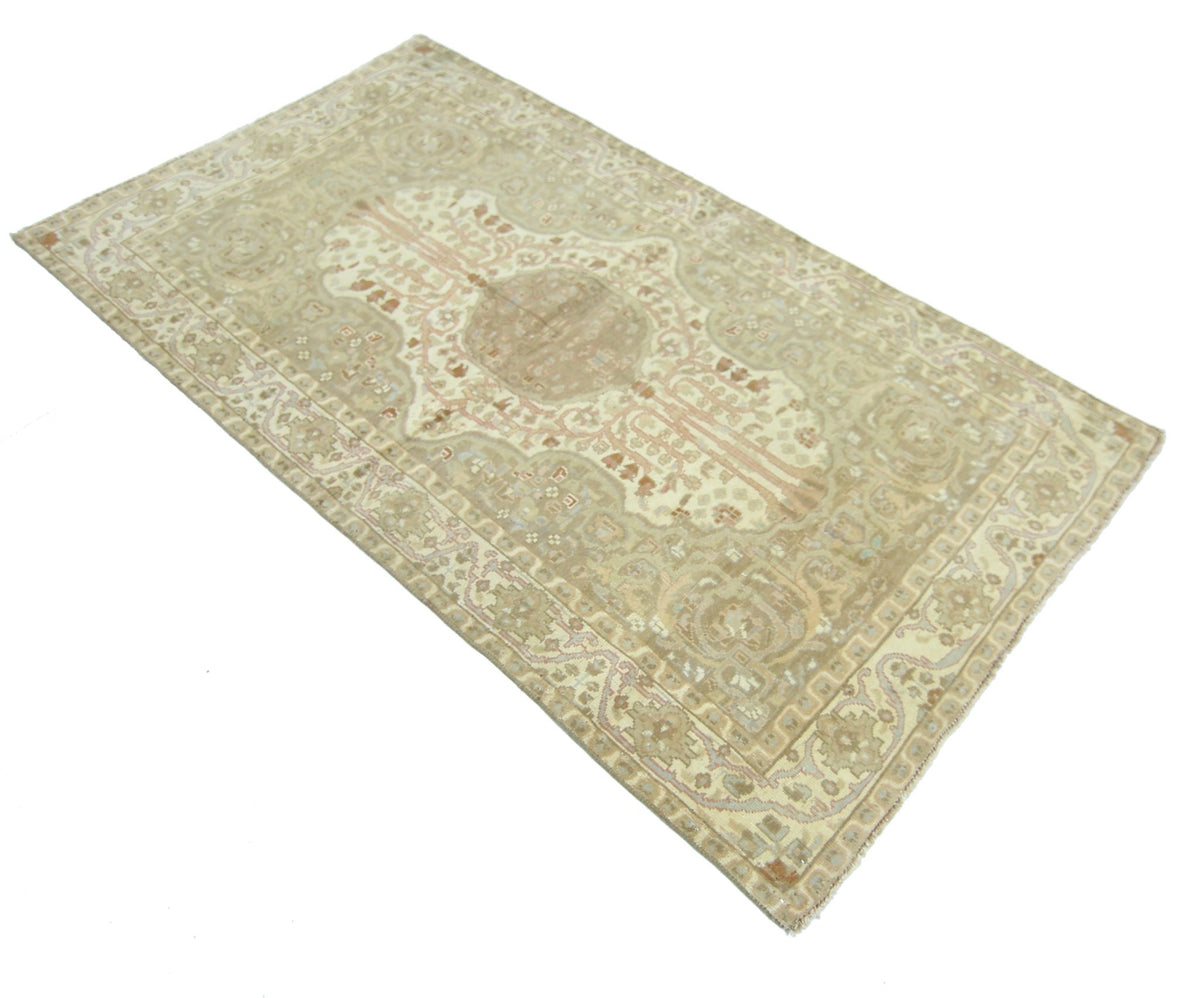 A vintage Pakistani rug featuring a traditional medallion pattern in muted beige and cream tones.