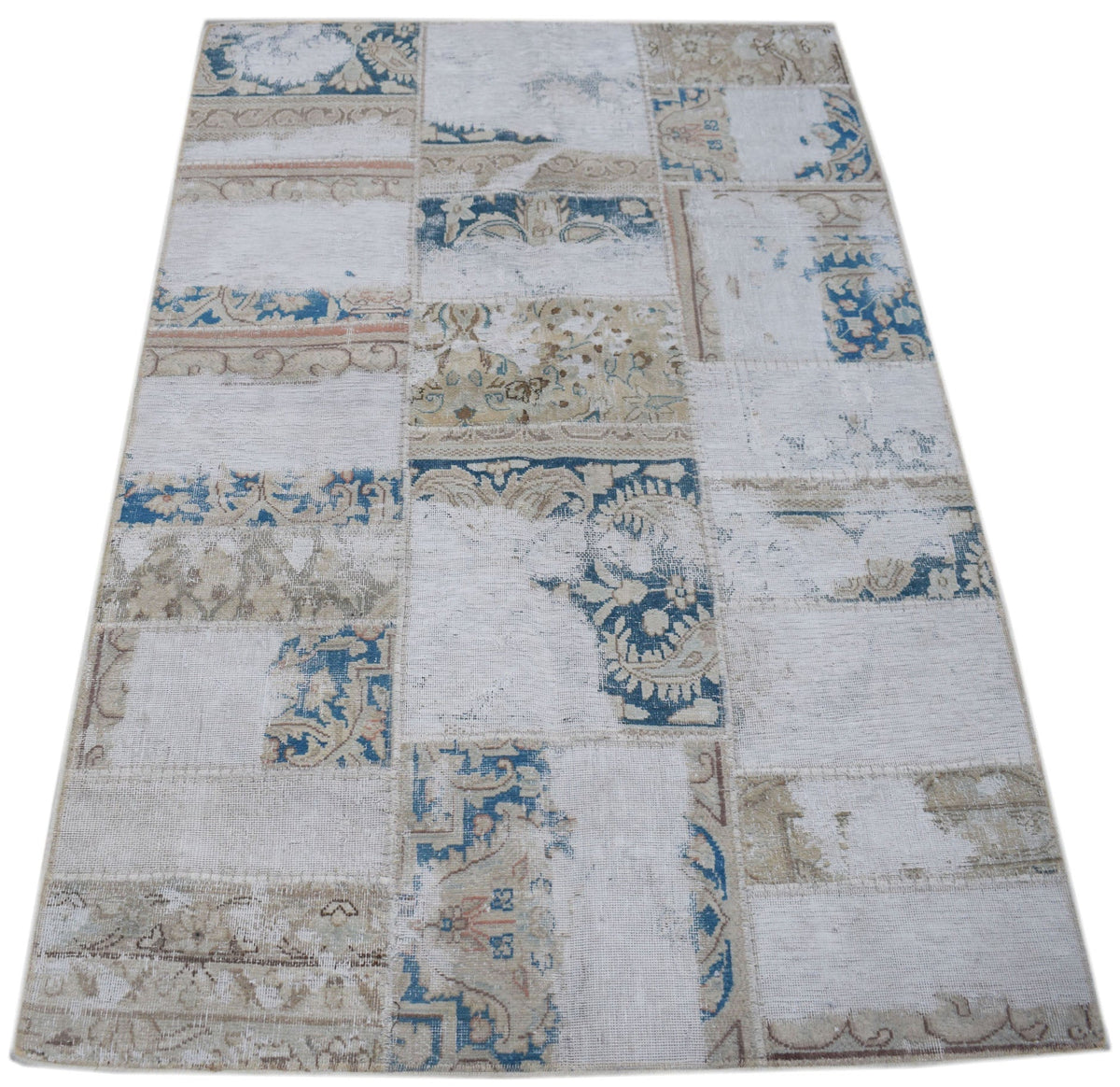A rectangular handmade patchwork rug featuring a distressed pattern of blue and beige floral motifs.