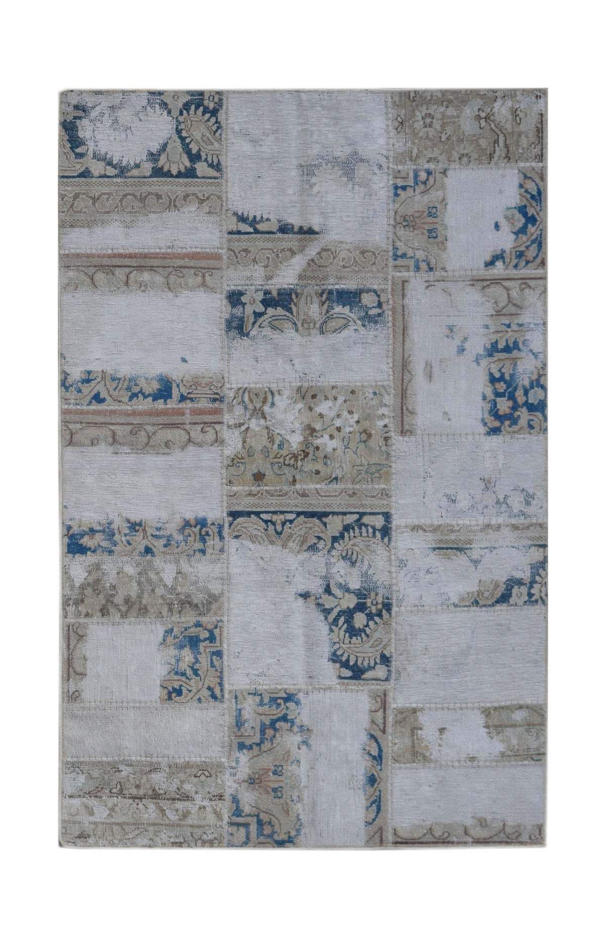 A rectangular handmade patchwork rug featuring a distressed pattern of blue and beige floral motifs.