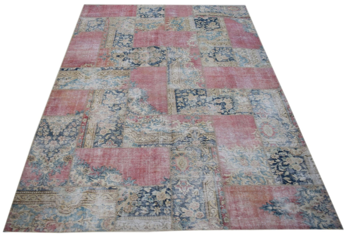 A rectangular vintage patchwork rug featuring a distressed pattern of pink and blue floral motifs.