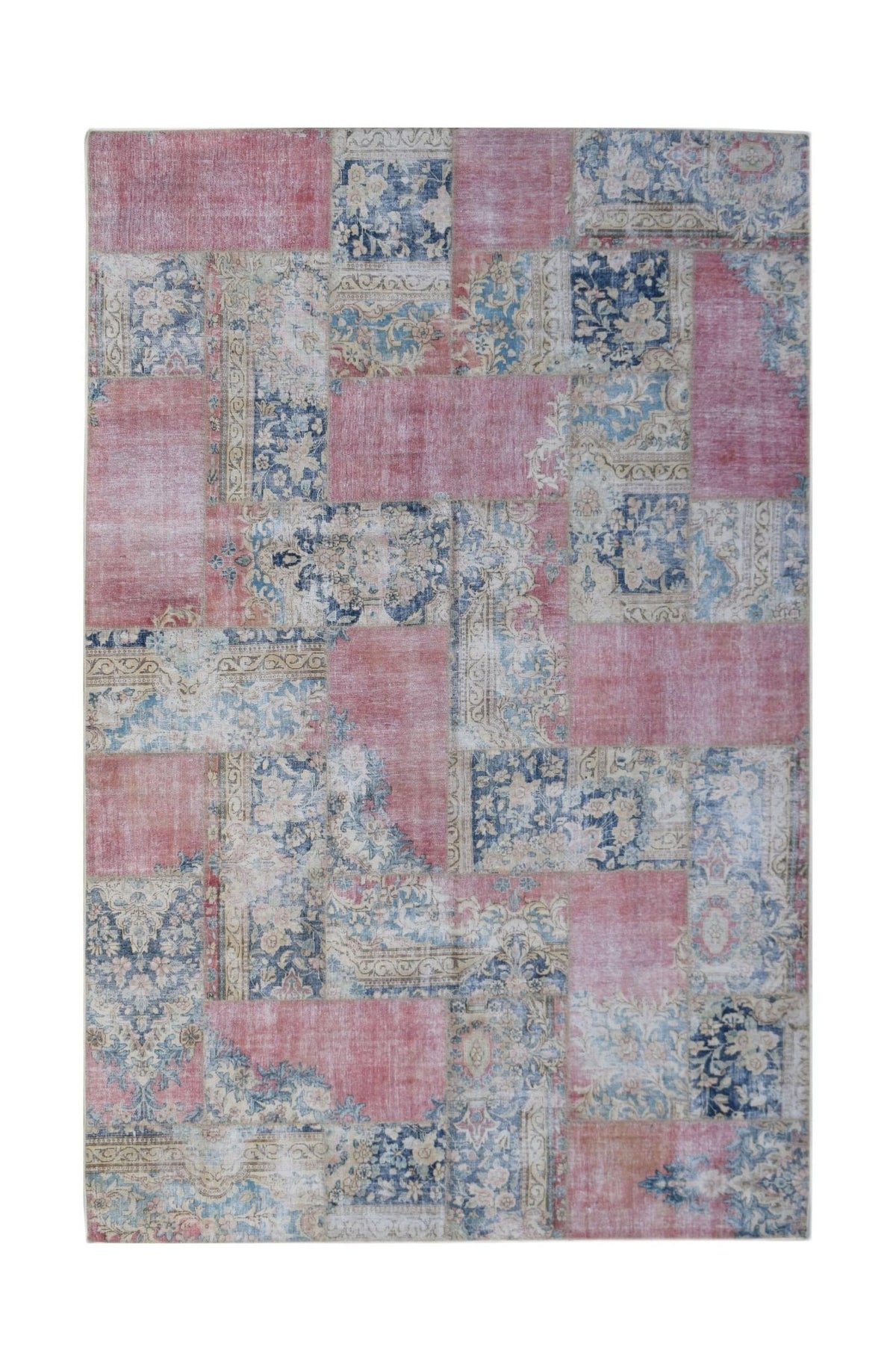 A rectangular handmade patchwork rug featuring a vintage design in shades of pink, blue, and cream.