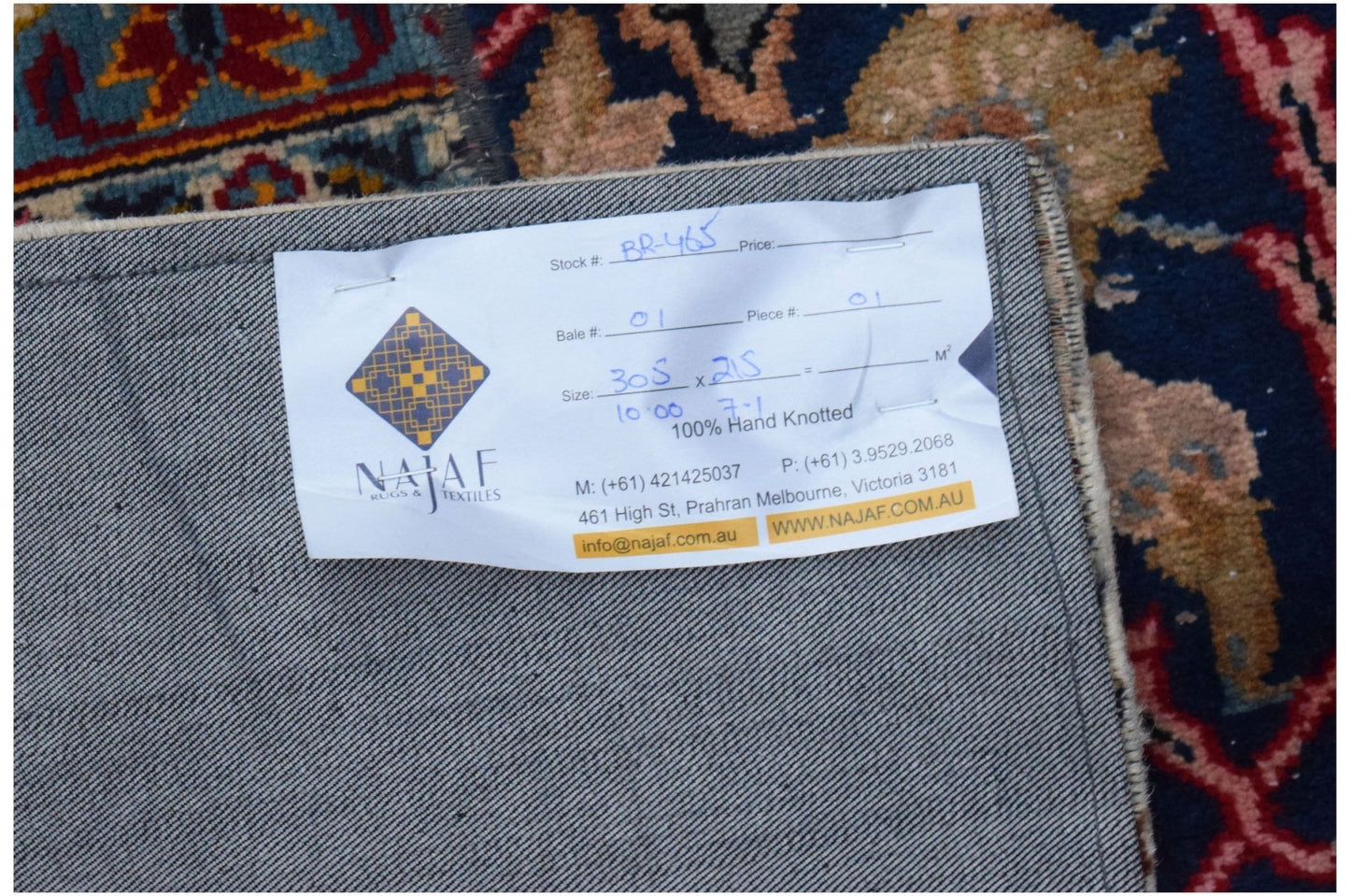 The underside of a handmade wool patchwork rug showing a product label from Najaf Rugs and Textiles.