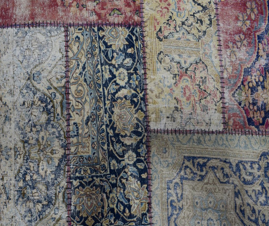 A handmade patchwork rug featuring various vintage floral patterns in blue, red, and beige tones.