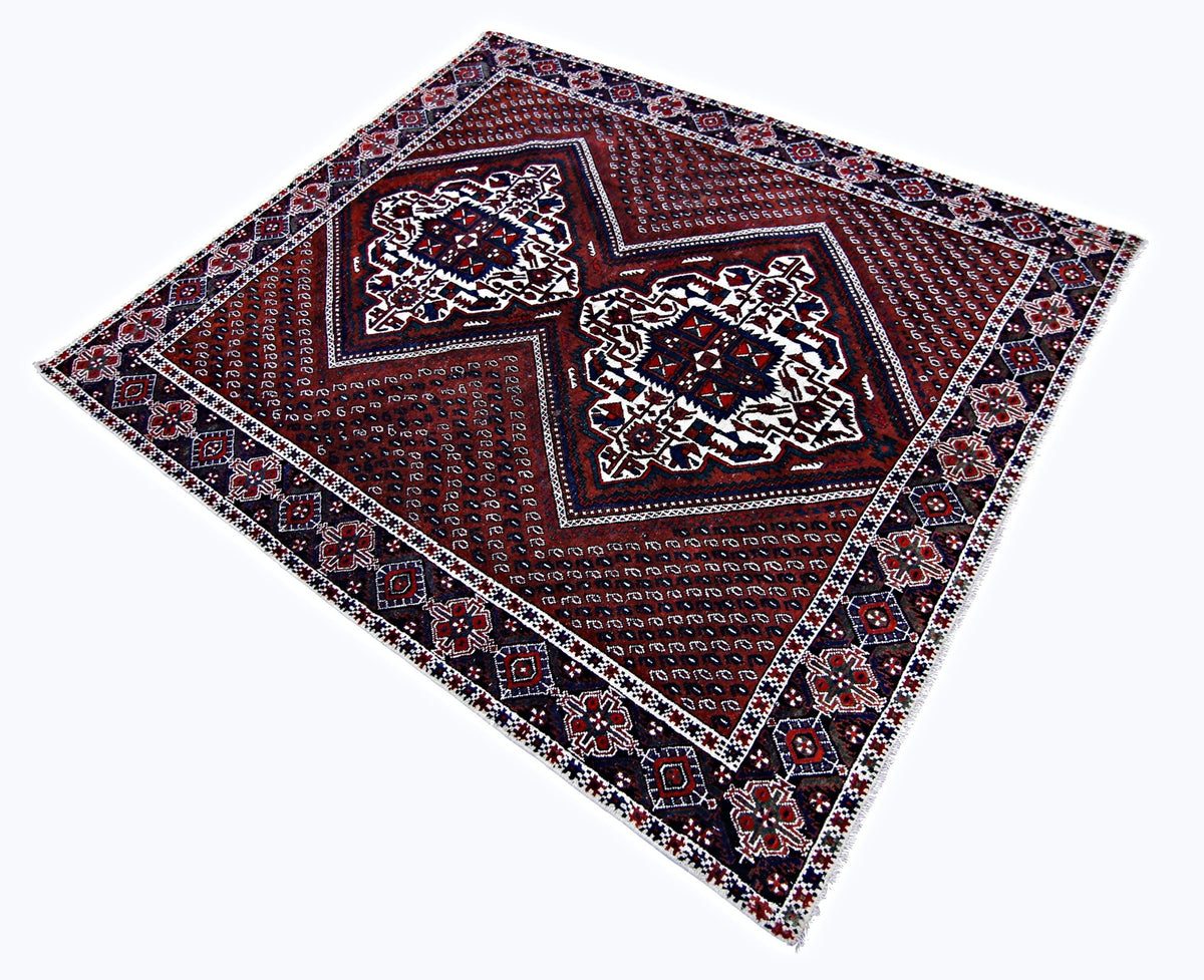 Vintage Persian Afshar rug with a deep red field, geometric medallions, and intricate blue and white tribal borders.
