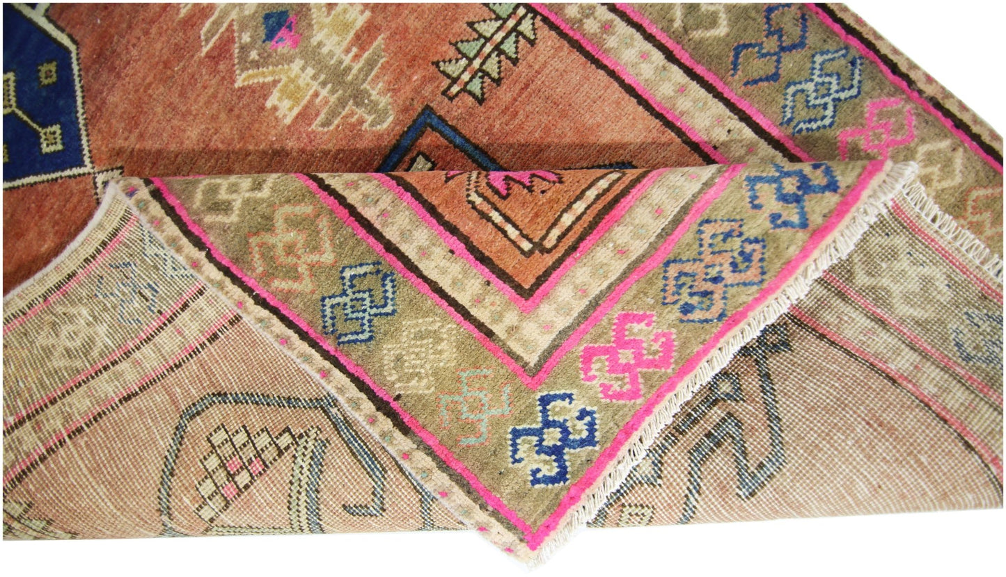A vintage Persian runner featuring geometric patterns in orange, blue, and pink on a wool pile.