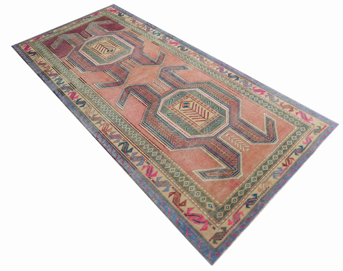 Vintage Persian Ardabil wool runner with geometric motifs in faded pink, blue, and green on a long, narrow format.