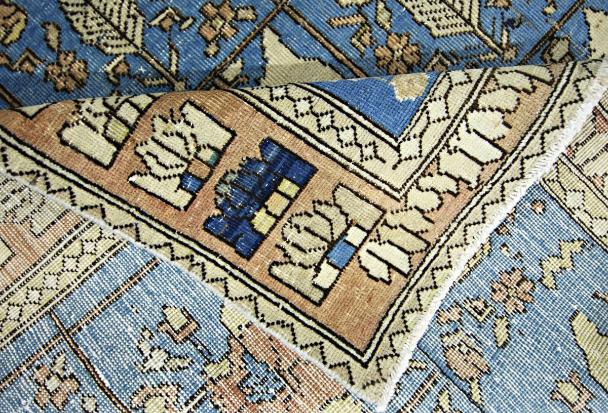 Close-up of a vintage Persian Bakhtiari rug featuring a blue and tan Khesti garden panel pattern with visible fringe.
