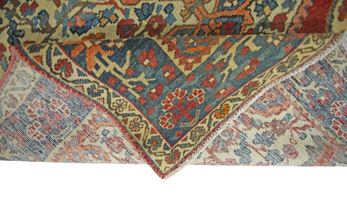 A vintage Persian Bakhtiari rug with a folded corner revealing its intricate floral pattern.