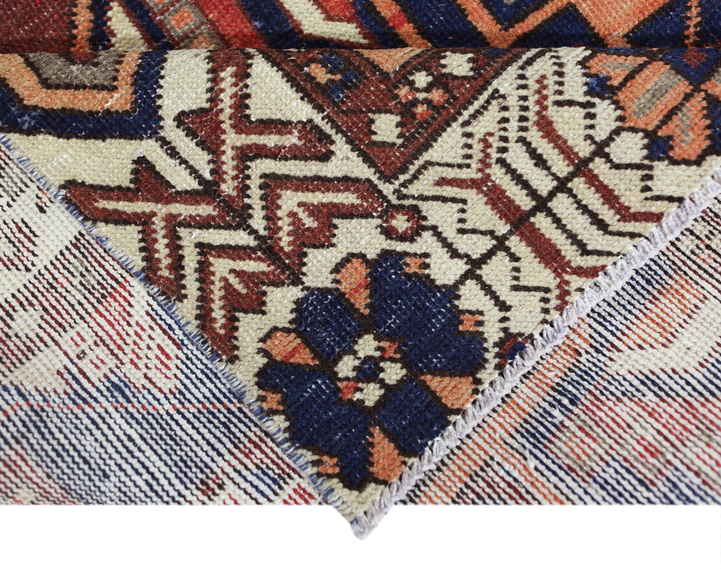 A close-up view of a vintage Persian Bakhtiari rug showing its intricate wool pile and cotton base.