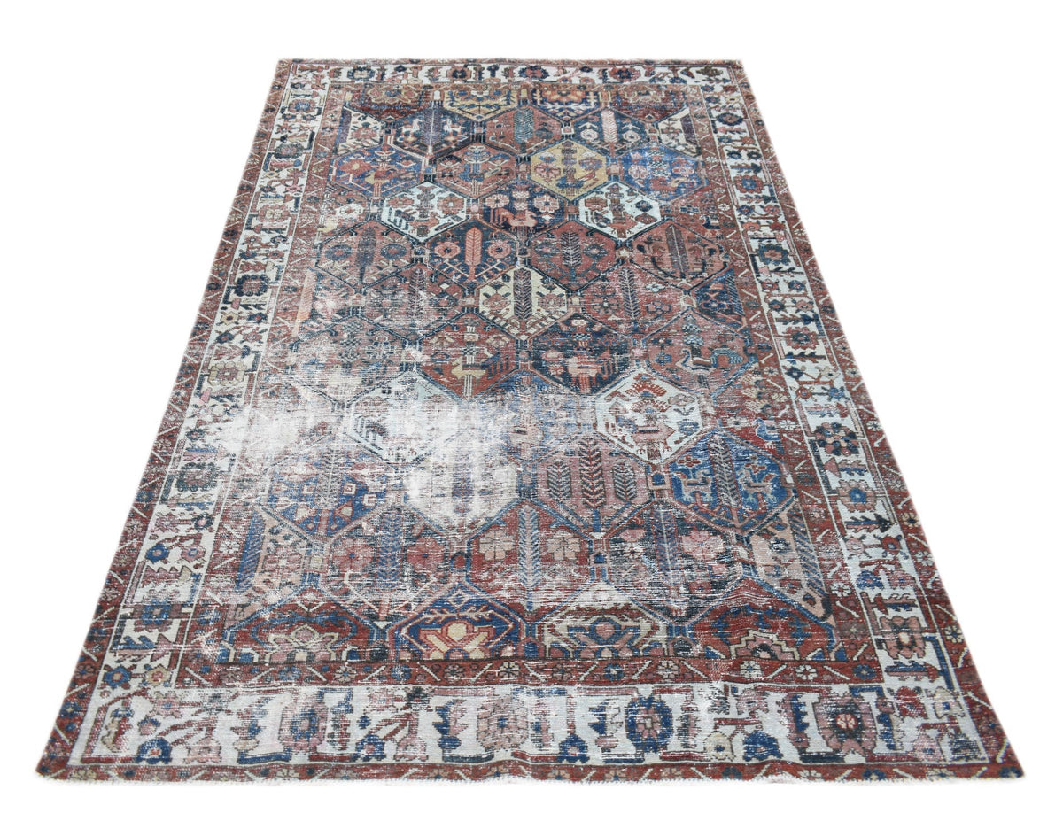 A vintage Persian Bakhtiari rug featuring a geometric pattern in faded red and blue tones.