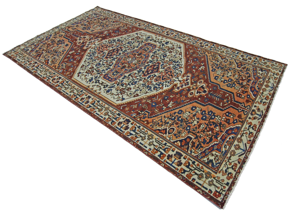 Vintage Persian Bakhtiari rug featuring a terracotta, blue, and cream Khesti garden panel design with intricate motifs.