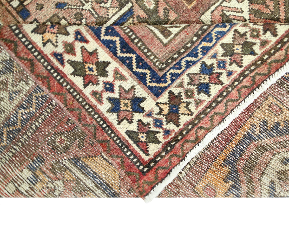 A corner of a vintage Persian Bakhtiari rug featuring intricate floral patterns in red and blue.