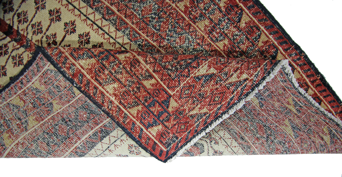 A vintage Persian Bakhtiari runner with a folded corner showing its intricate red and cream pattern.