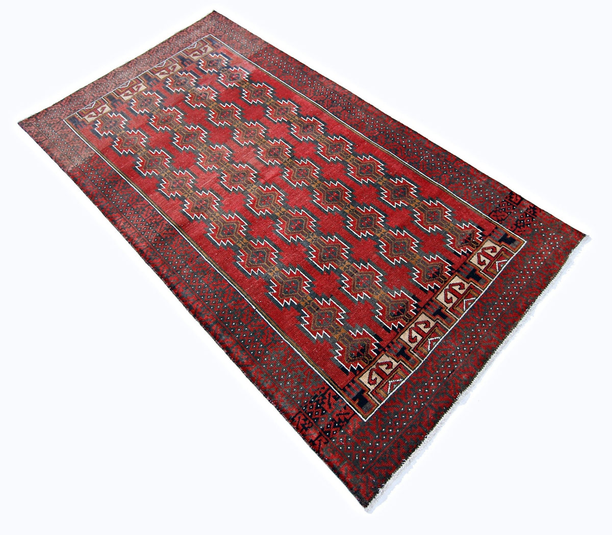 Hand-knotted Persian Baluch rug featuring geometric medallions in deep red, earthy tones, and wool construction with a fringed edge.