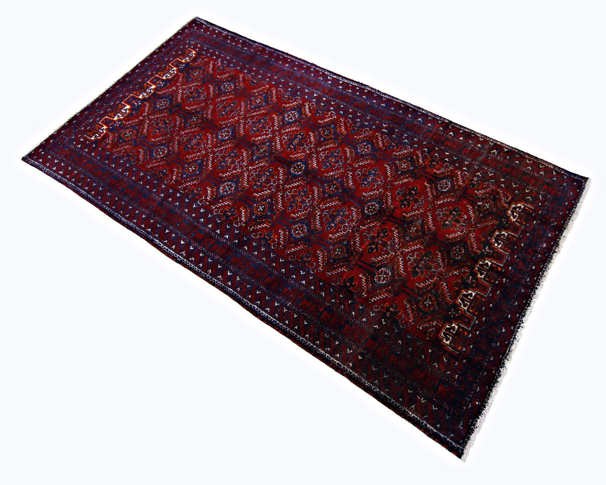 Hand-knotted Persian Baluch rug featuring geometric medallions in deep red and navy wool with a traditional fringed edge.
