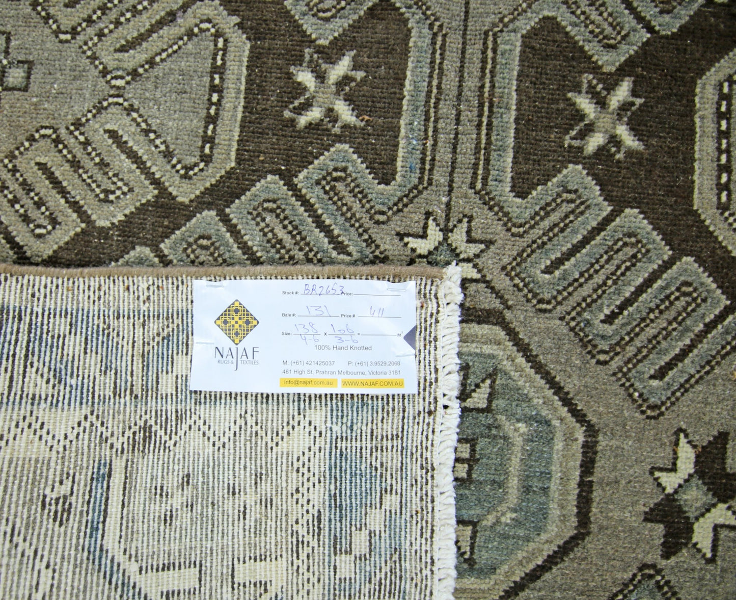 A vintage Persian rug featuring a geometric pattern in shades of brown and grey.
