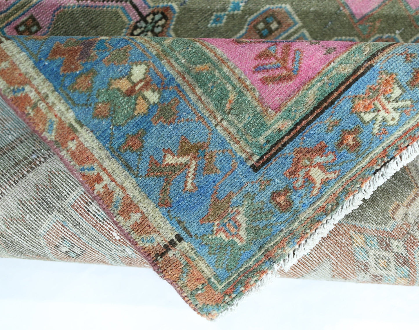 A folded vintage Persian Hamadan rug featuring a vibrant blue, pink, and green floral pattern.