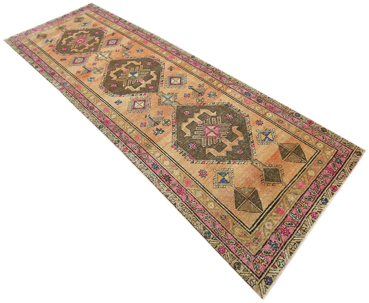 Hand-knotted vintage Hamadan runner with brown and orange geometric medallions, tribal motifs, and a pink floral border.