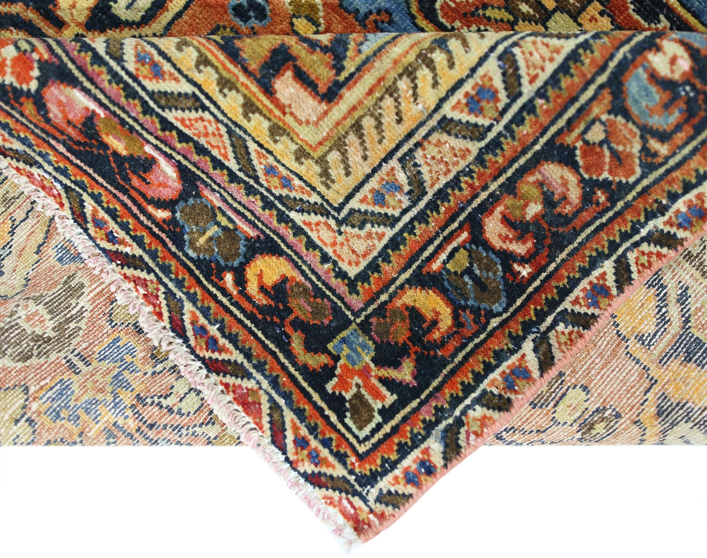 A corner view of a vintage Persian Heriz rug featuring intricate geometric patterns in wool.