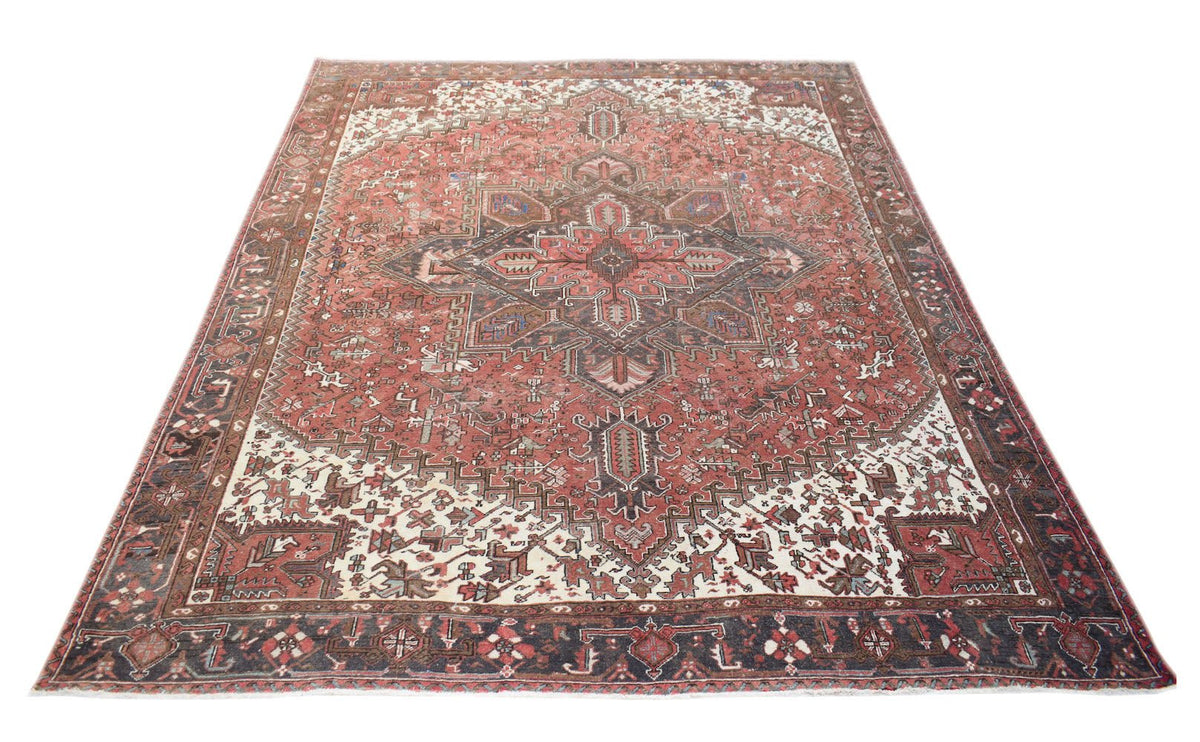 A vintage handwoven Persian Heriz rug featuring a geometric medallion on a terracotta field.