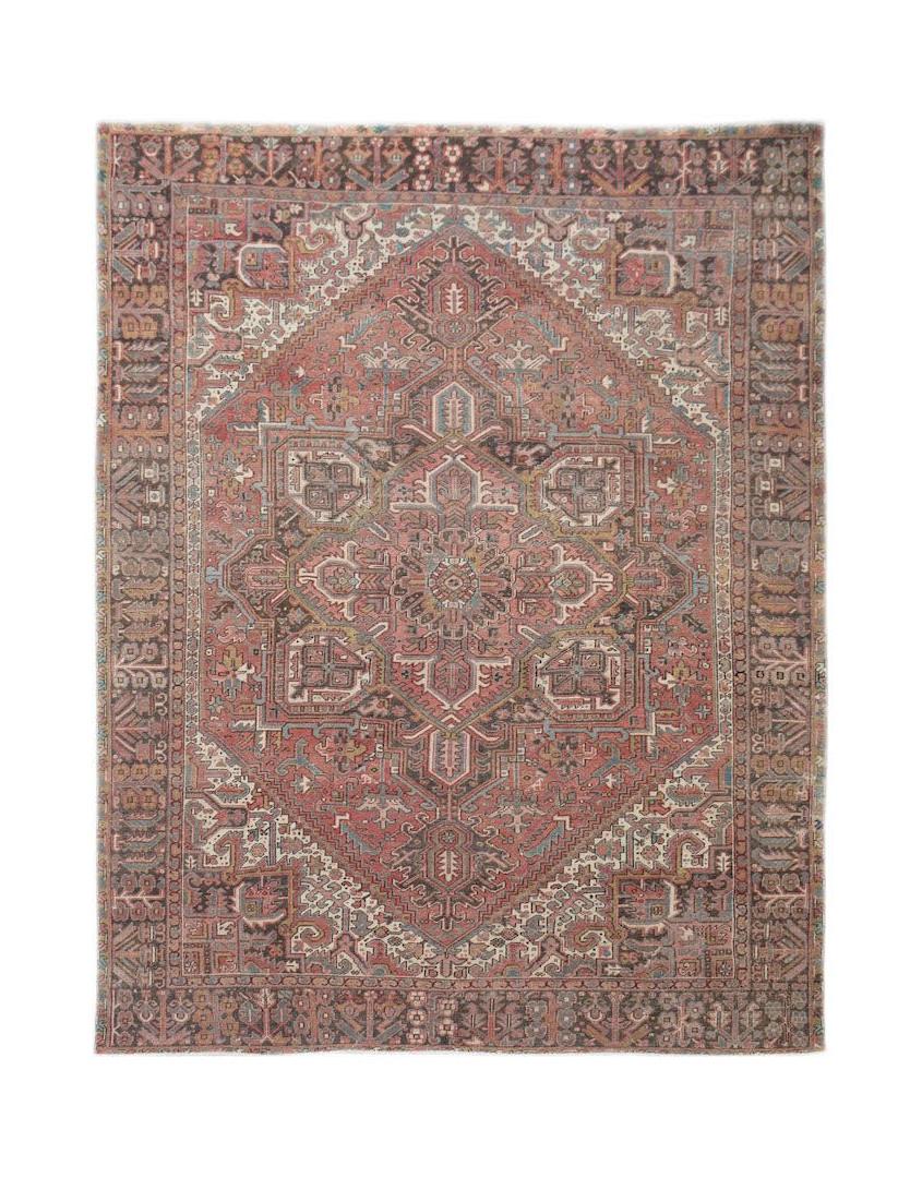 A vintage handwoven Persian Heriz rug featuring a geometric medallion in muted red and blue tones.