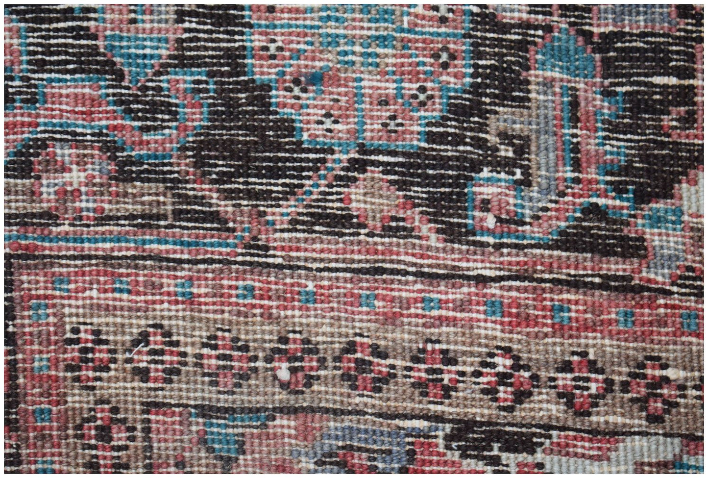 A close-up view of a vintage Persian Heriz rug featuring intricate geometric patterns in wool.