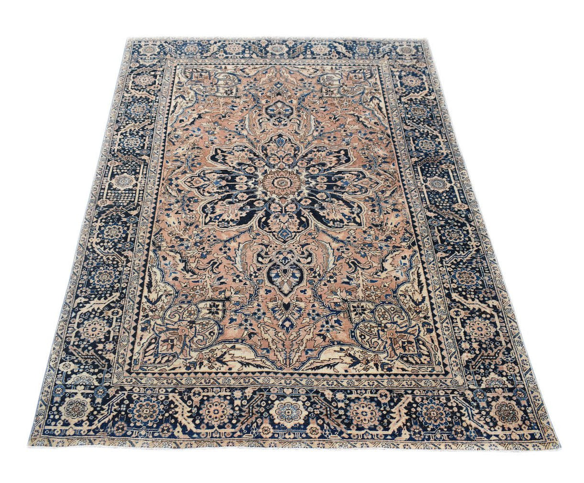 Vintage Persian Heriz rug featuring a central floral medallion on a tan field with blue borders.