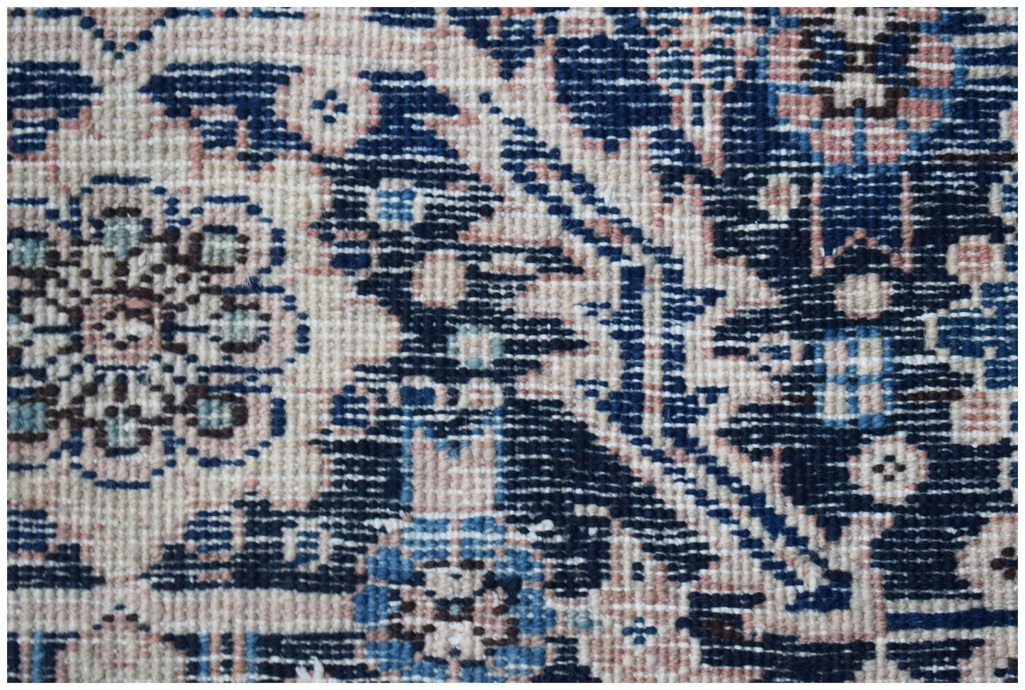 A close-up of a vintage Persian Heriz rug featuring intricate floral patterns in blue and cream.