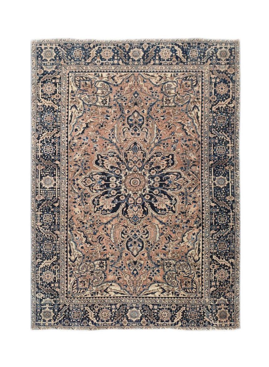 A vintage handwoven Persian Heriz rug featuring a central floral medallion in blue and tan tones.
