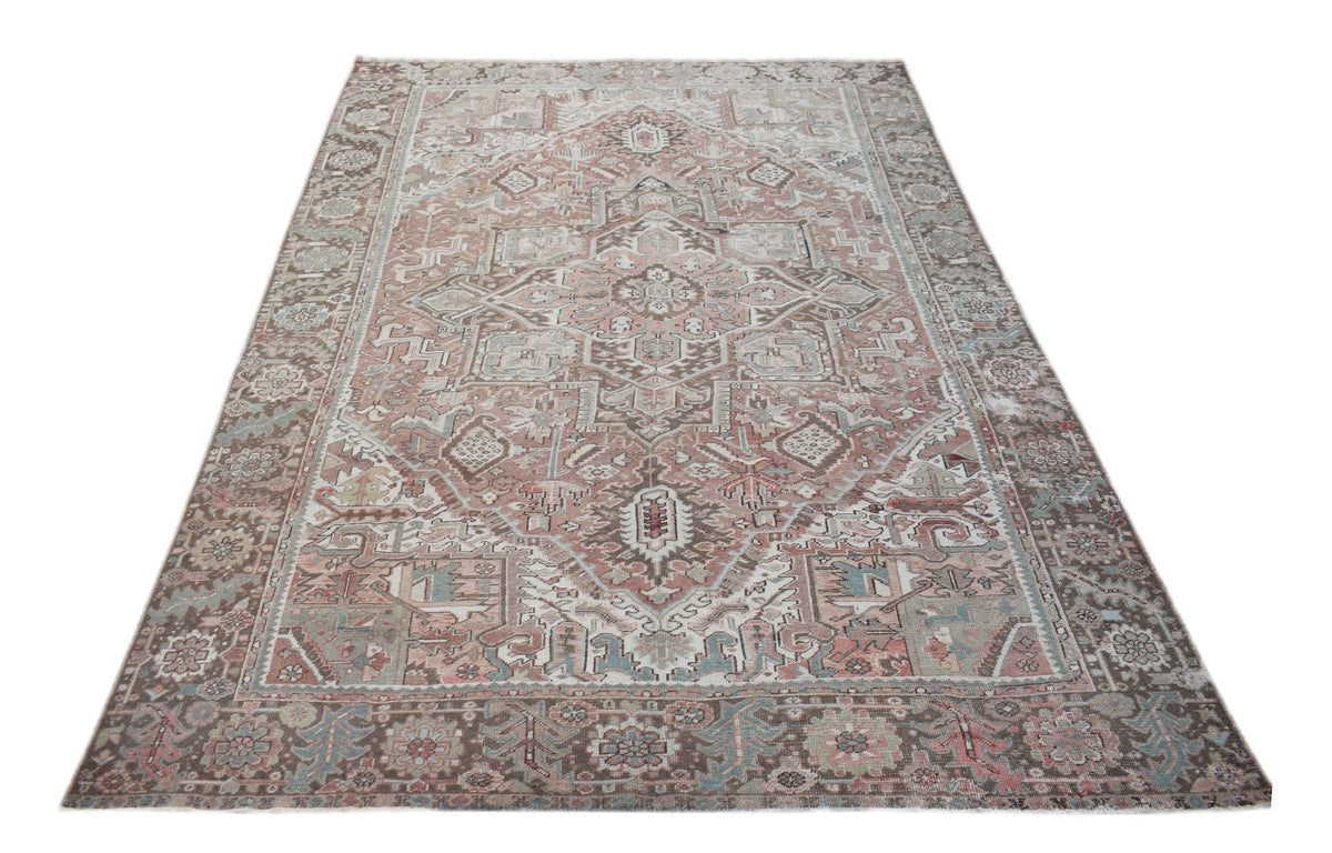 A vintage handwoven Persian Heriz rug featuring a geometric medallion in muted earth tones.