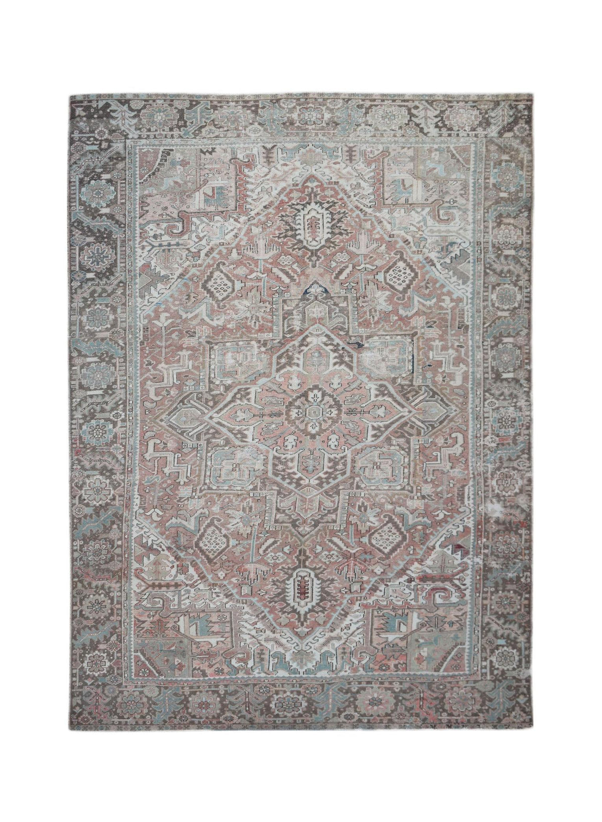 A vintage handwoven Persian Heriz rug featuring a geometric medallion in muted pink and brown tones.