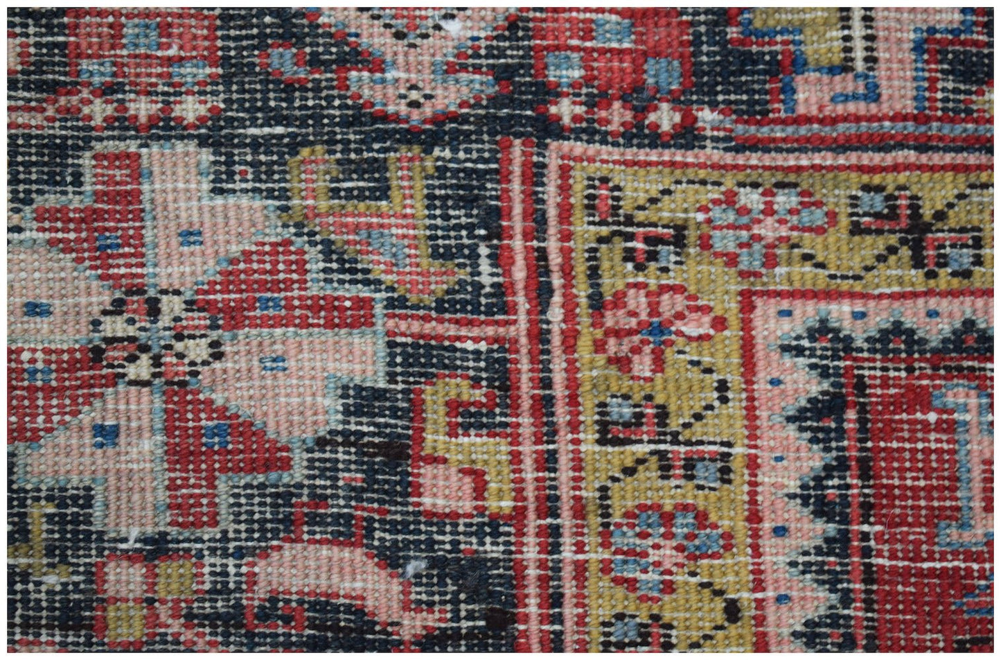 A close-up of a vintage Persian Heriz rug featuring intricate geometric floral patterns in wool.