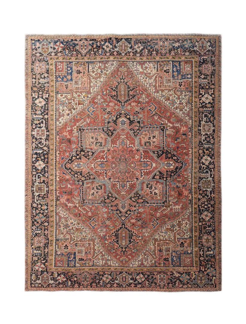 A vintage handwoven Persian Heriz rug featuring a large central medallion on a rust red field.