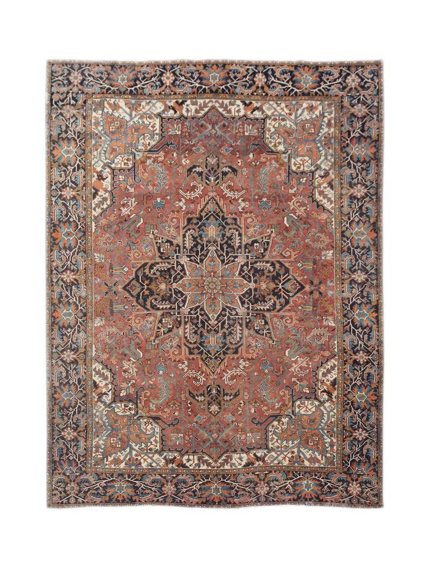 A vintage Persian Heriz rug featuring a central medallion on a rust red field with floral borders.