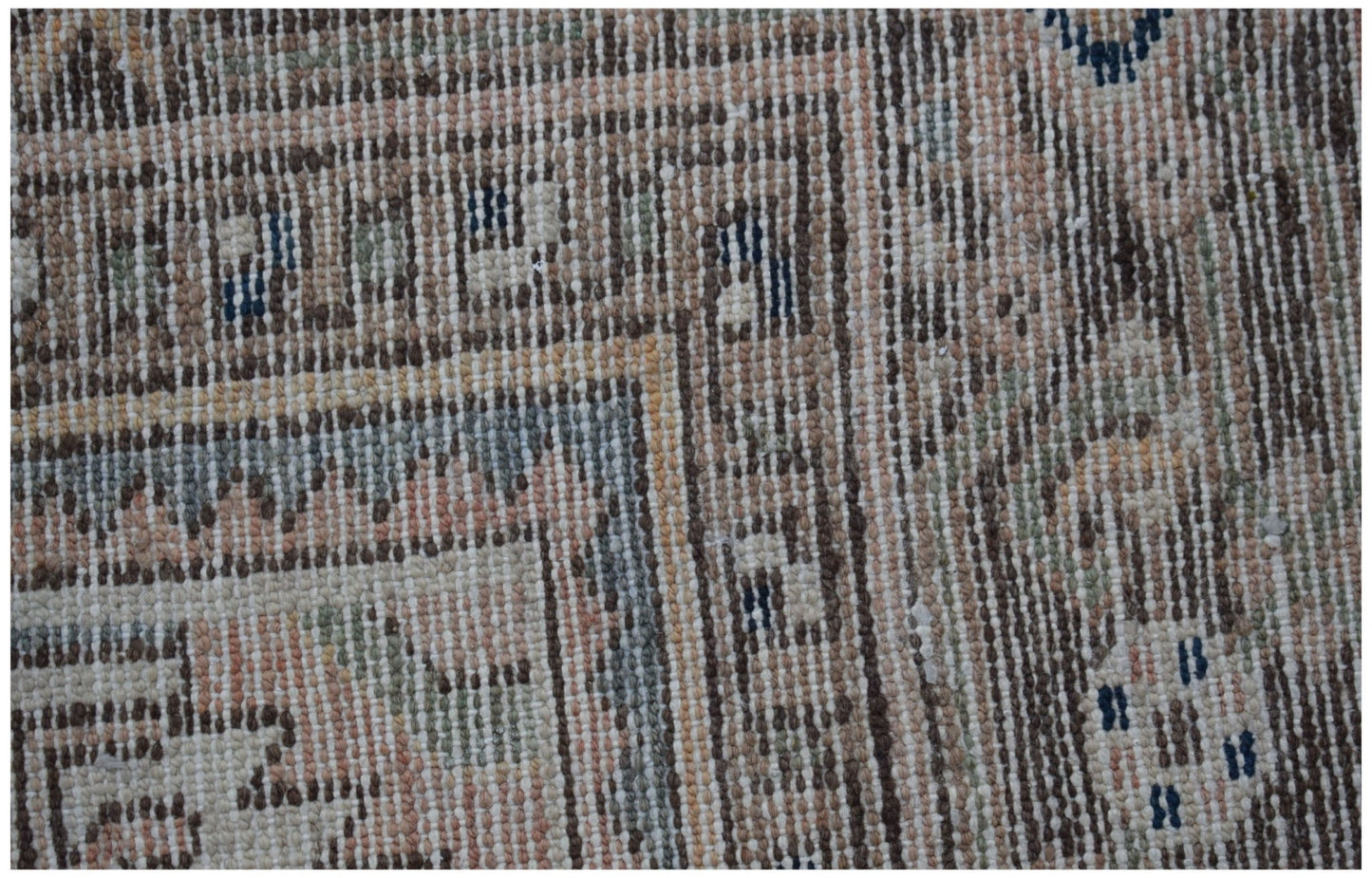 A close-up of a vintage Persian rug featuring intricate geometric patterns in muted earth tones.